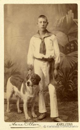 Foto av pojke i sjömanskostym med hund vid sin sida, ur CE Nygrens porträttsamling