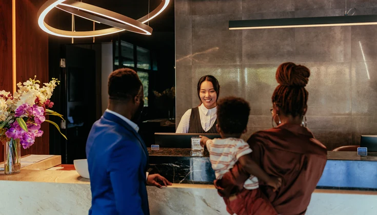 En receptionist på ett hotell hjälper en familj att checka in.