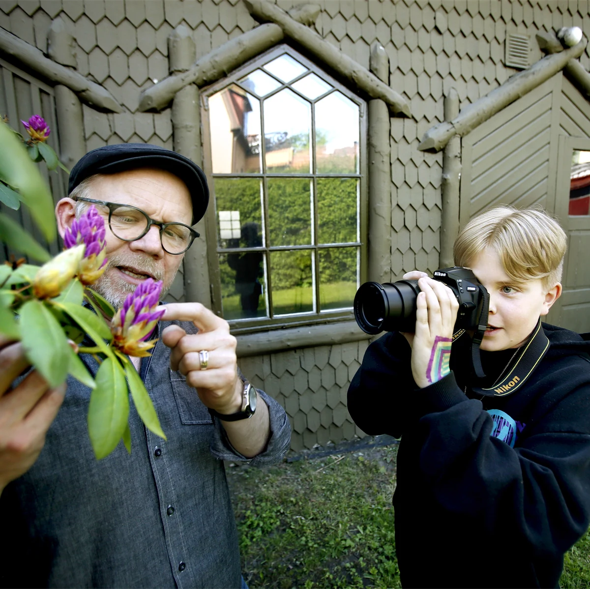 Pojke som fotar en blomma utomhus