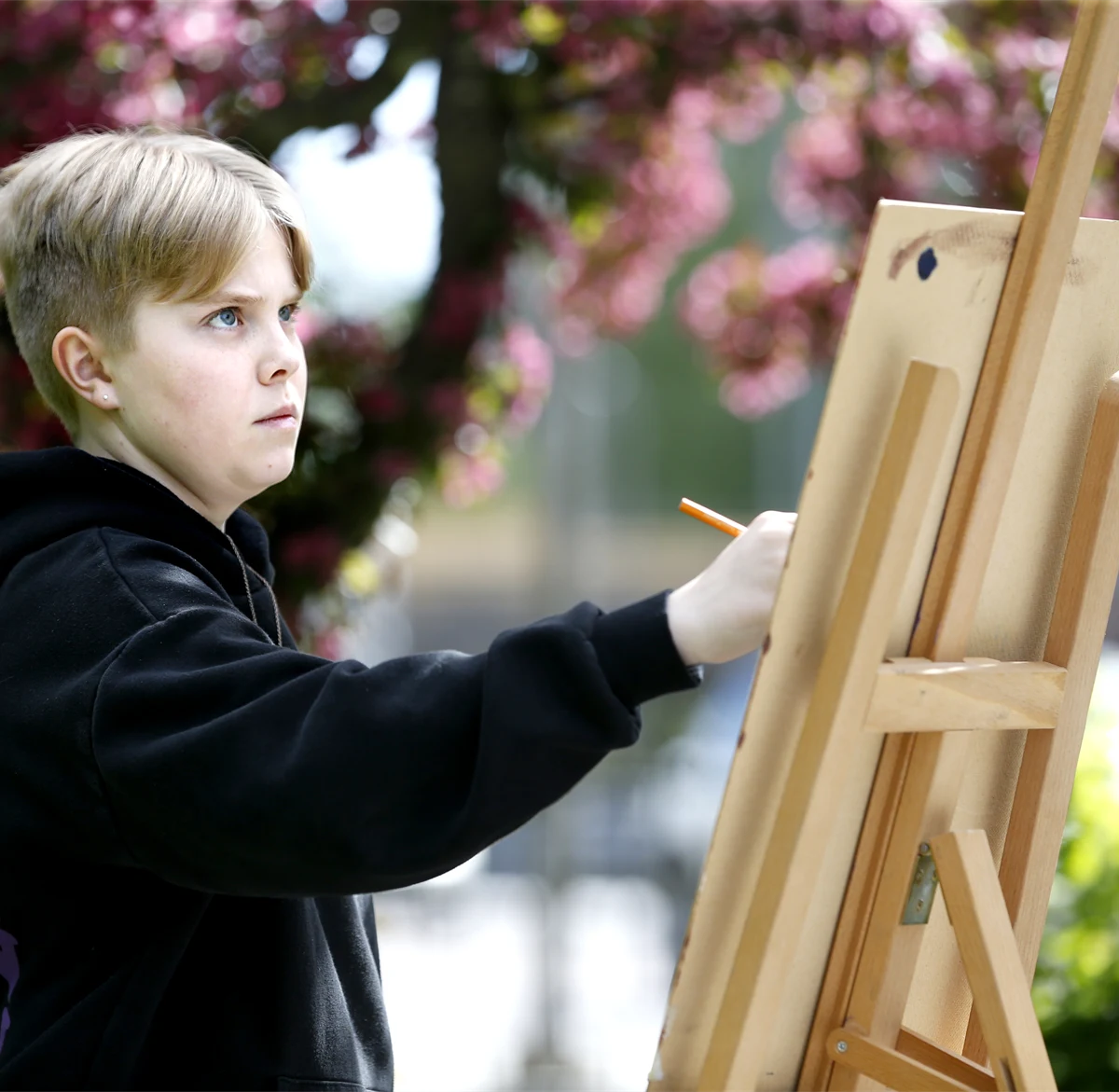 Pojke som målar på ett staffli utomhus
