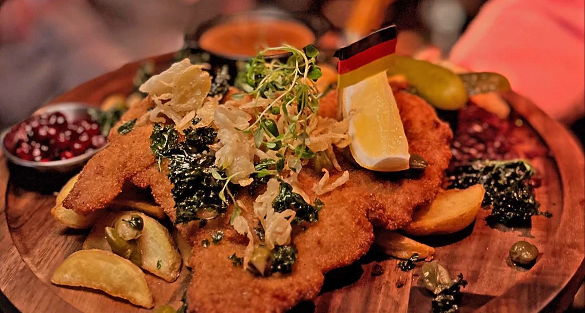 En snitzel med citron upplagd på ett fat av trä.