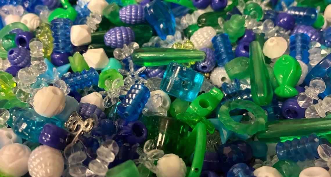En hög med plastpärlor i blått, grönt och vitt