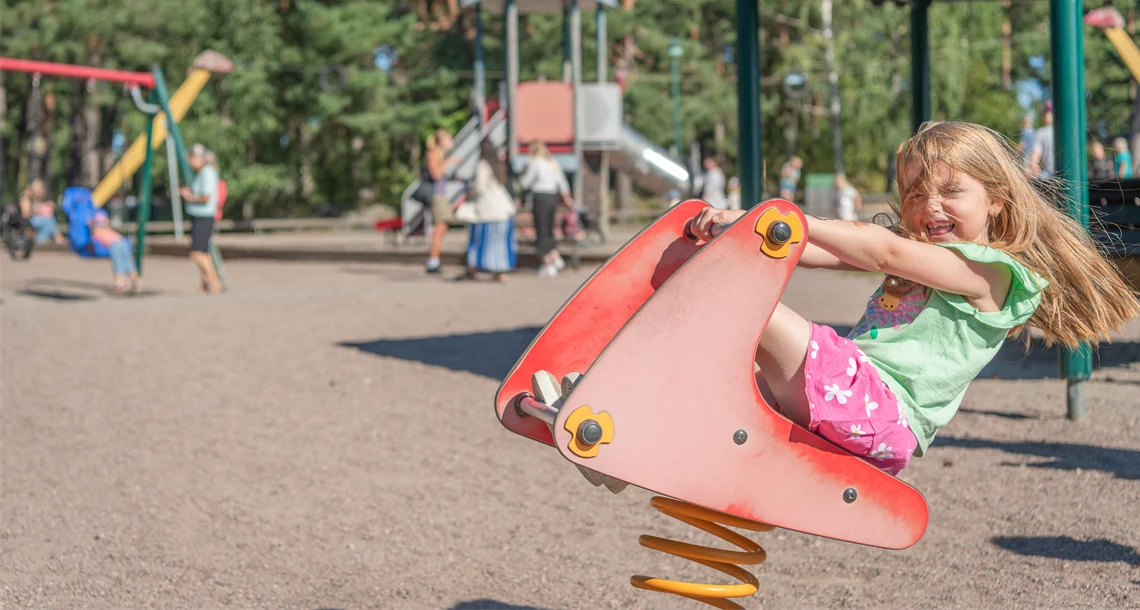 Flicka på gunghäst i lekpark. 