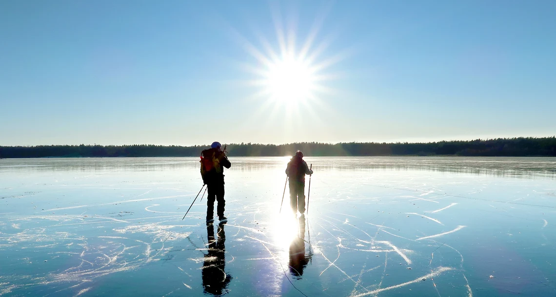 Två personer åker skridskor på sjö