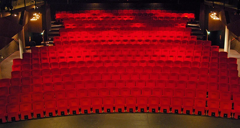 En stor teatersal med många rader med röda fåtöljer
