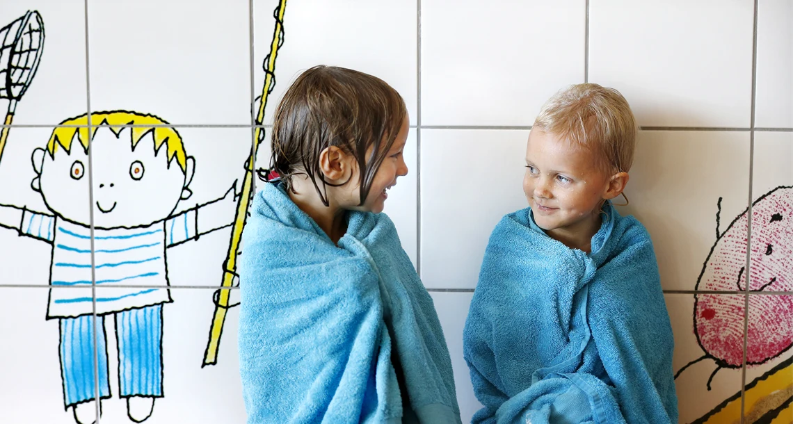 Två barn i upplevelsebadet i handduk
