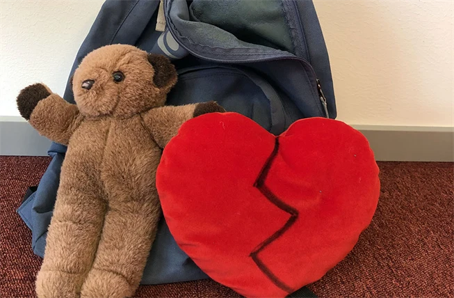 Ryggsäck intill en nallebjörn och ett tyghjärta