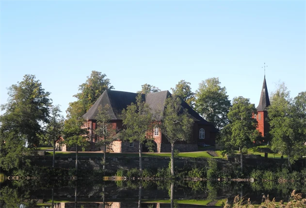 röd kyrka med vattendrag i förgrunden. 