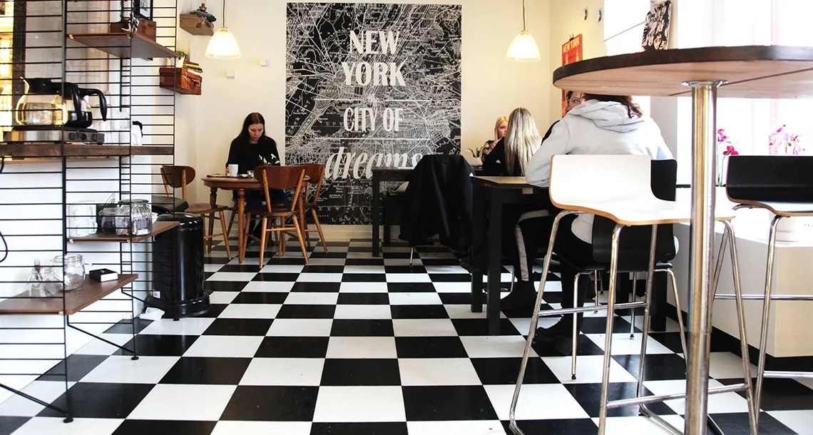 Folka sitter och fikar i ett rum med schackrutigt golv