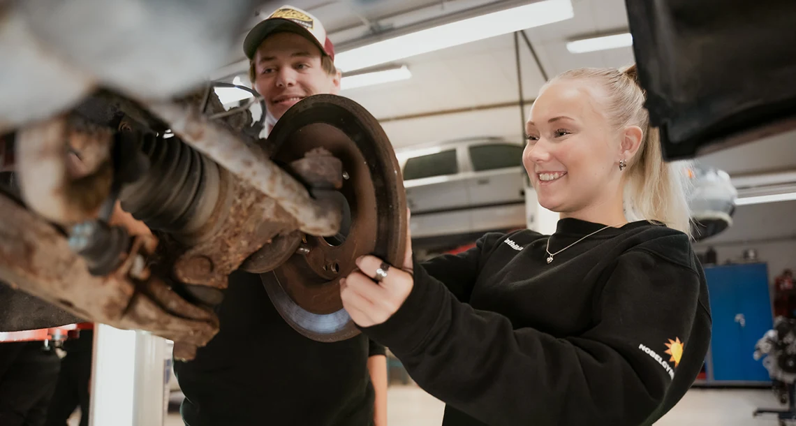 Två elever mekar i fordonsverkstadsmiljö.