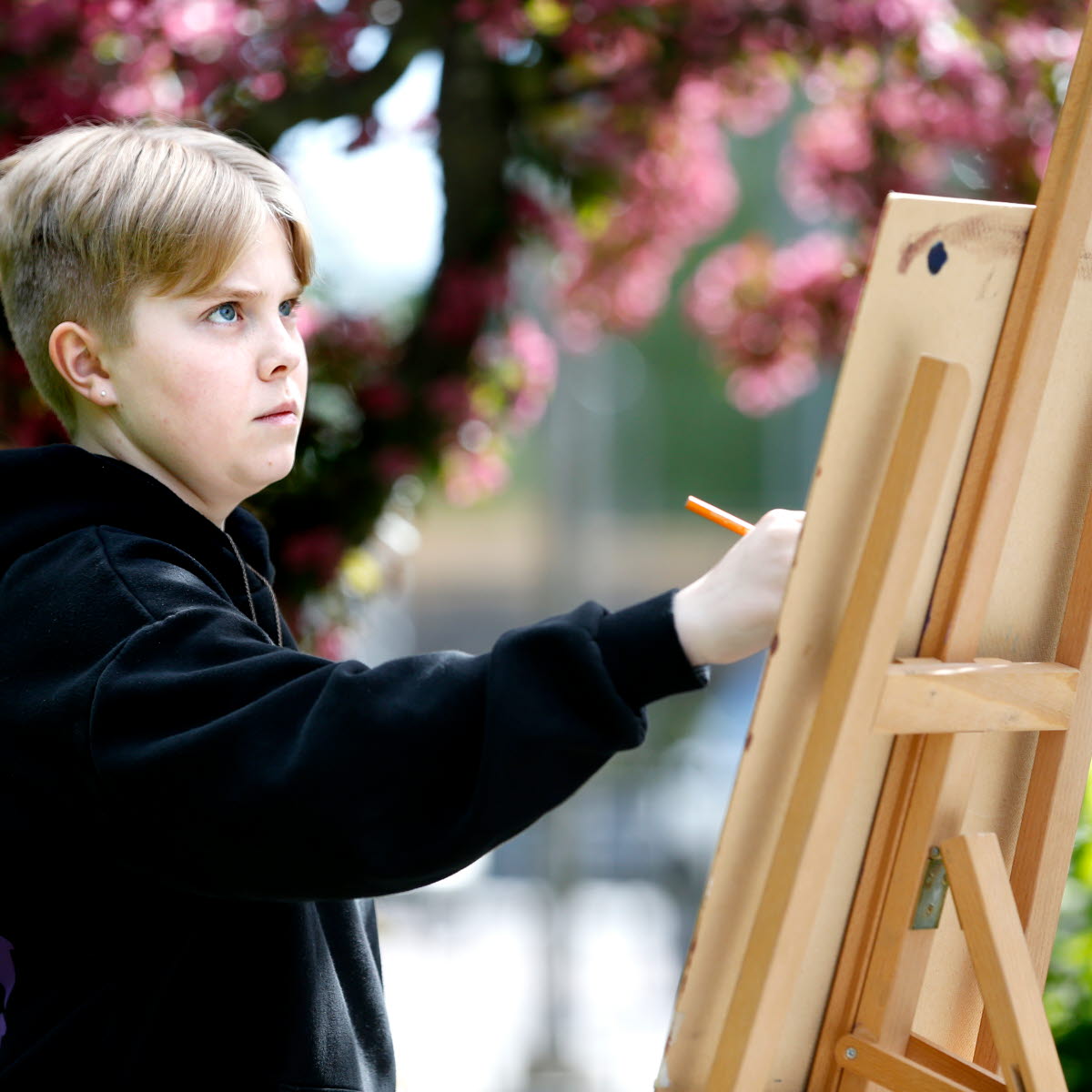 Pojke som målar på ett staffli utomhus