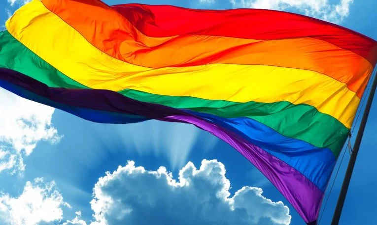 Prideflagga med blå himmel bakom.