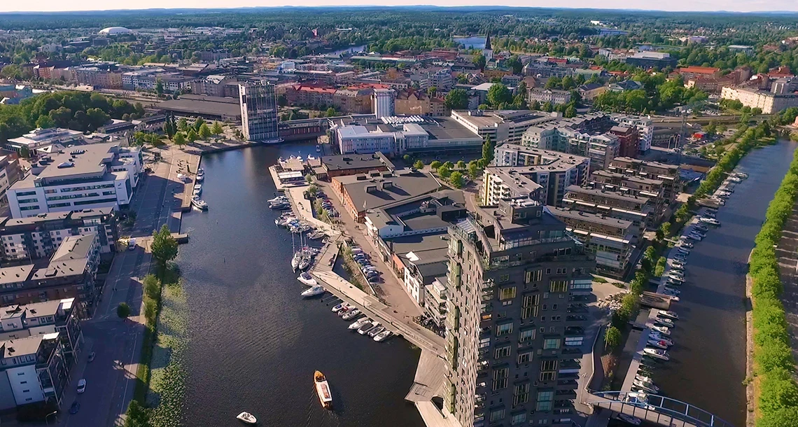 En flygbild över en stad med en hamn med förtöjda båtar.