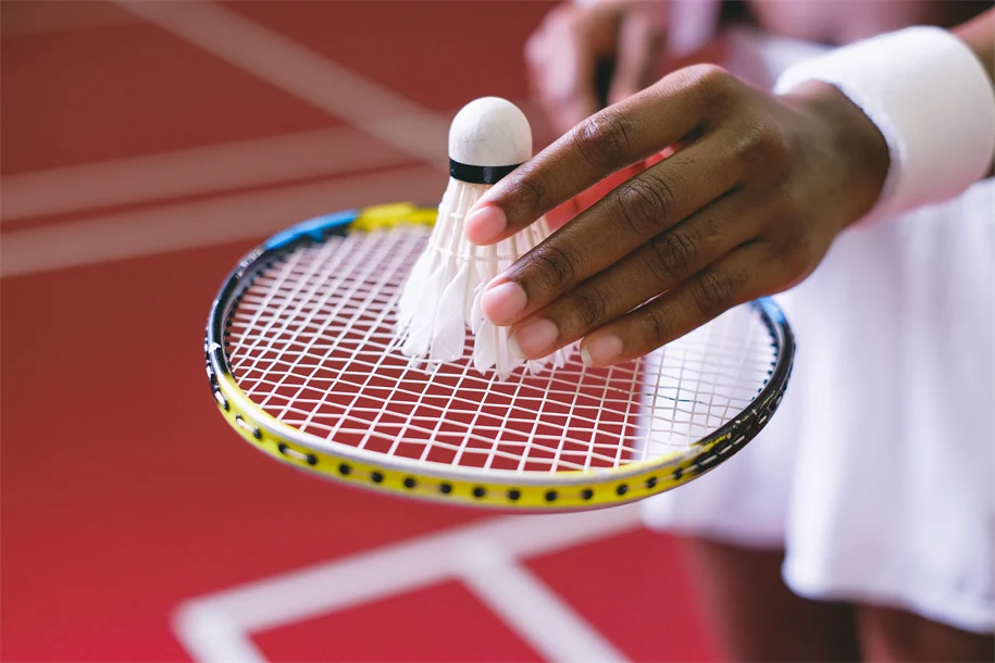 Händer som håller ett badmintonrack och en badmintonboll