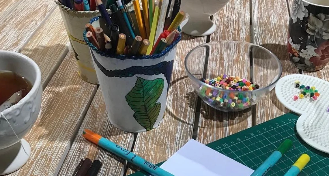 Pennor i en mugg och papper på ett bord