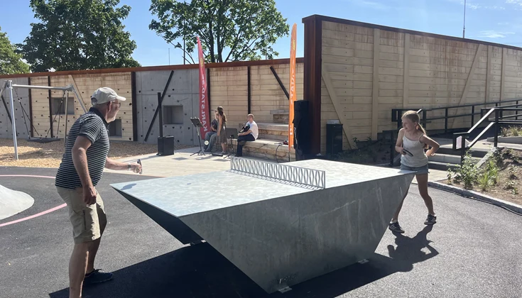 Två personer som spelar pingis och ett band i bakgrunden