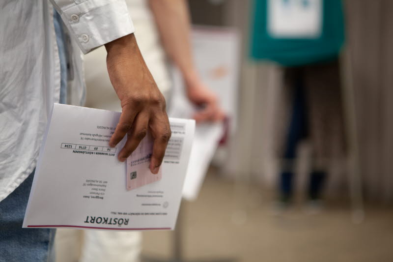 Väljare med röstkort och id-handling i handen