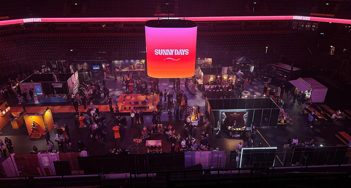 En stor utställningshall med människor som tittar och minglar bland olika montrar