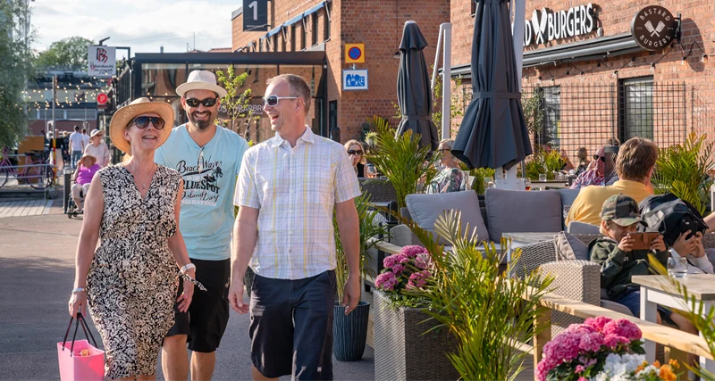 tre människor går förbi en uteservering