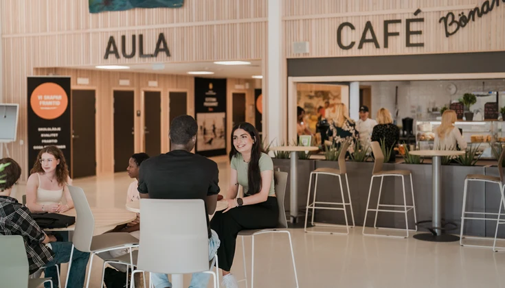 Elever som sitter vid cafébord i skolans cafeteria.