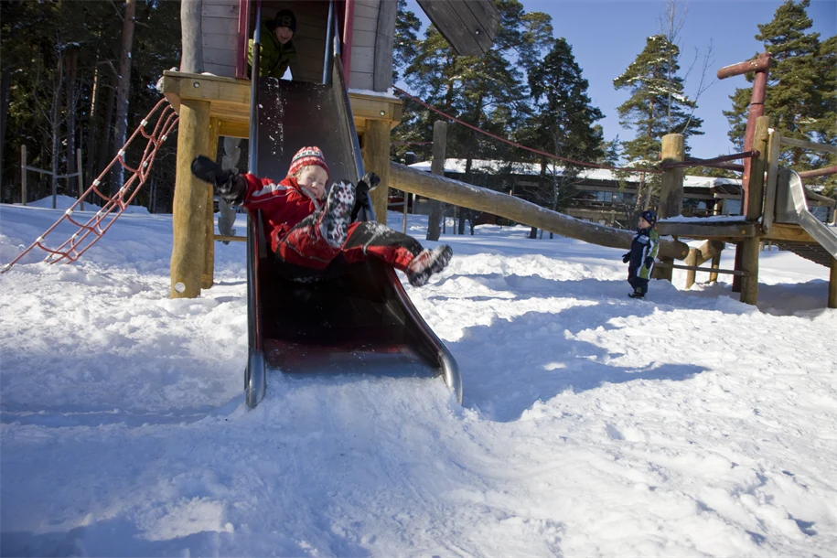 Barn åker rutchkana på vintern.