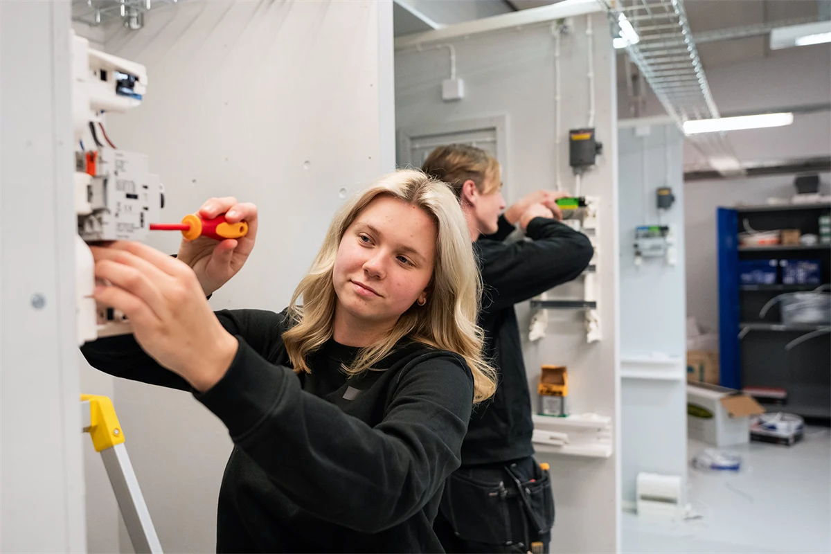 Två gymnasieelever skruvar i elcentraler.