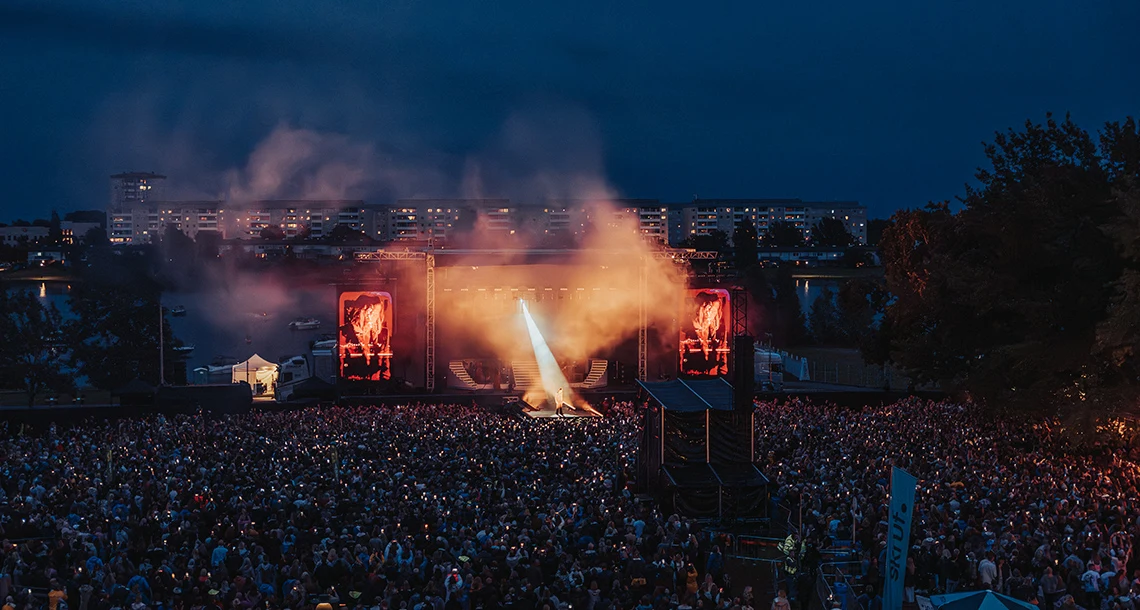 En stor nedsläckt scen med en artist på framför ett stort folkhav