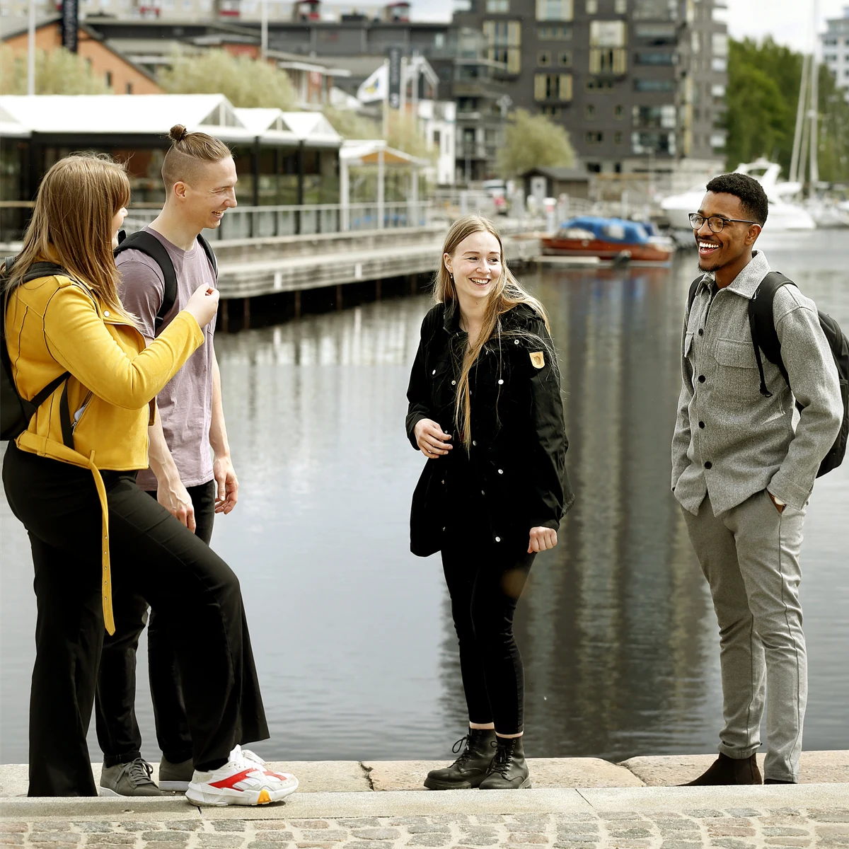 Fyra studenter med vatten och hus i bakgrunden.