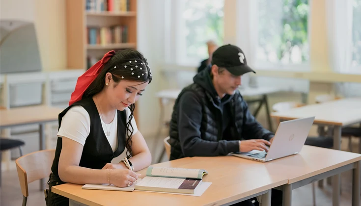 Två elever studerar i klassrumsmiljö.