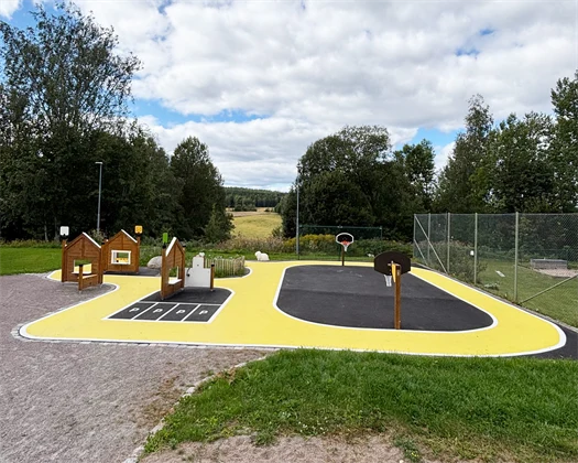 Asfalterad plan med en cykelbanan som ska föreställa en liten by och en mindre bollplan med låga basketkorgar.