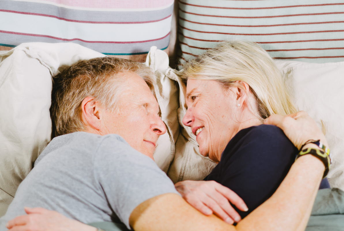 Man och kvinna ligger i en säng och kramar om varandra