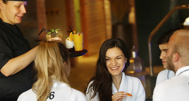 Konferensdeltagare i badrockar blir serverade juice