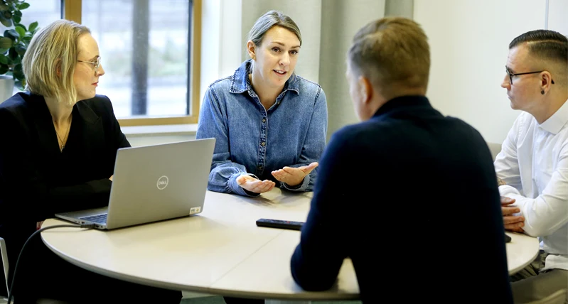 Fyra personer har möte runt bord.