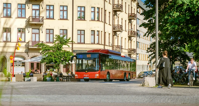 Gata i förgrunden, buss och bostäder i bakgrunden.
