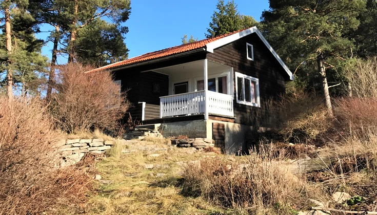 Ett brunt och vitt fritidshus omgivet av natur