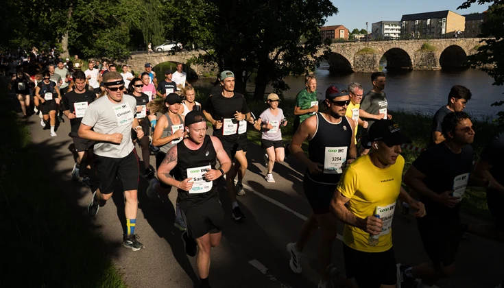 Massor av människor springer ett motionslopp. Solen skiner och det är sommar.