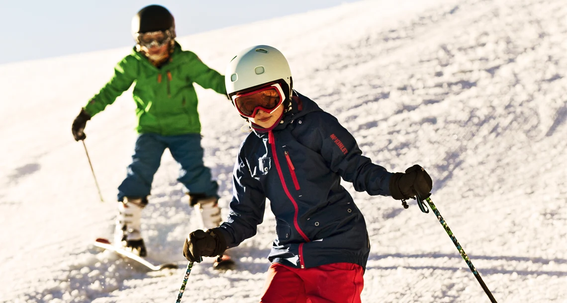 Två barn åker slalom i Bryngfjordens slalombacke.