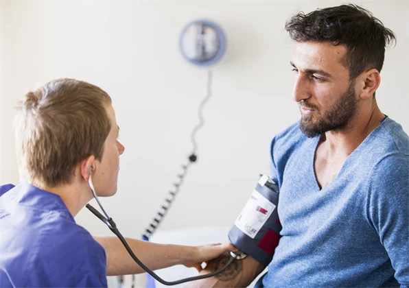 Person tar blodtryck på en patient.