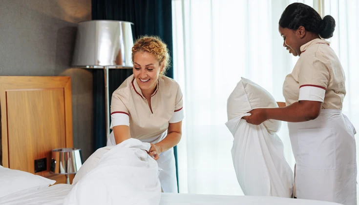 Två personer bäddar en hotellsäng.