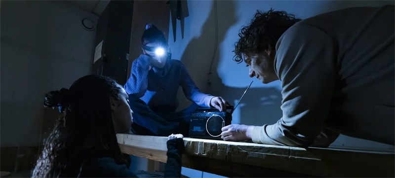 Personer som lyssnar på radio i ett mörk rum.