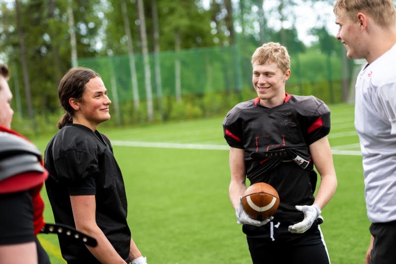 Elever från idrottsgymnasiet i rugbykläder pratar med varandra